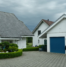 Suburban homes with blue garage doors illustrating uneven door operation concerns.