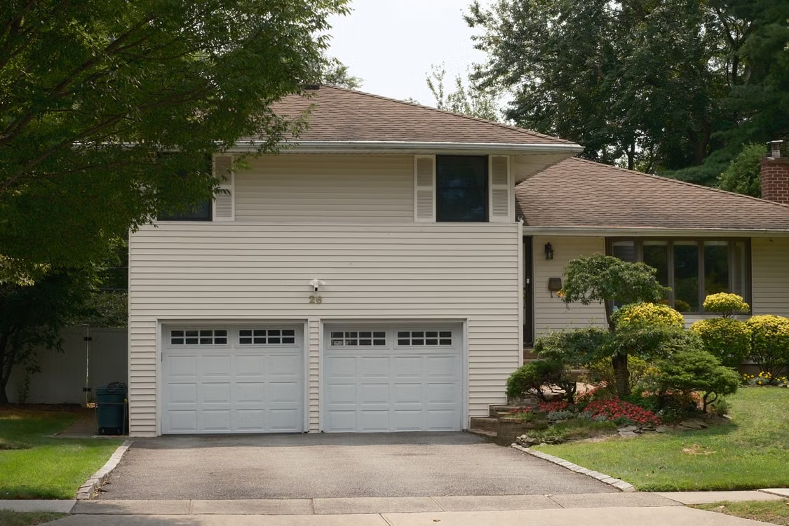 Suburban home with double garage representing routine maintenance for quieter door operation.